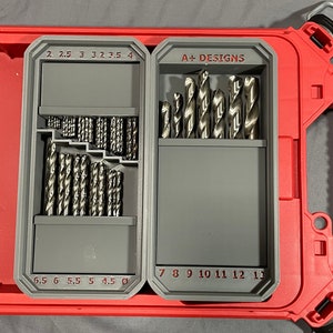 May include: A grey plastic drill bit organiser with two compartments. The top compartment has drill bits labelled 2, 2.5, 3, 3.2, 3.5, and 4. The bottom compartment has drill bits labelled 6.5, 6, 5.5, 5, 4.5. The second compartment has drill bits labelled 7, 8, 9, 10, 11, 12, and 13. The organiser has the text "A+ DESIGNS" printed on the side.
