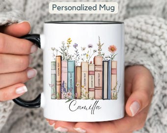 Puede incluir: Taza de cerámica blanca con asa y borde negros, con un diseño floral y de libros. La taza tiene el texto "Personalized Mug" en la parte superior y el nombre "Camilla" en la parte inferior. Los libros tienen el texto "Custom Text".