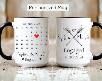 Puede incluir: Taza de cerámica blanca con asa negra. Un lado presenta un calendario con la fecha 10 de octubre de 2024 resaltada en rojo. El texto "Sophia & Mark Engaged" está impreso debajo del calendario. El otro lado de la taza presenta dos flechas cruzadas con un corazón en el centro. El texto "Sophia Mark Engaged 10/10/2024" está impreso debajo de las flechas.