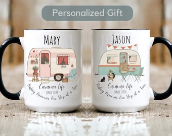 May include: Two white ceramic mugs with black handles. The mugs feature a colorful illustration of a caravan with the text "Caravan life since 2024" and "Making memories one stop at a time". One mug has the name "MARY" and the other has the name "JASON".