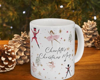 May include: White ceramic mug with a handle, featuring a Christmas theme. The mug is decorated with illustrations of ballerinas in pink tutus, toy soldiers, Christmas trees, and stars. The text "Charlotte's Christmas Mug" is also printed on the mug.