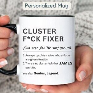 Könnte beinhalten: Weißer Keramikbecher mit schwarzem Henkel und Rand. Der Becher trägt den Text "CLUSTER F*CK FIXER" mit einer Definition und dem Namen "JAMES". Der Becher ist mit "Personalized Mug" beschriftet.