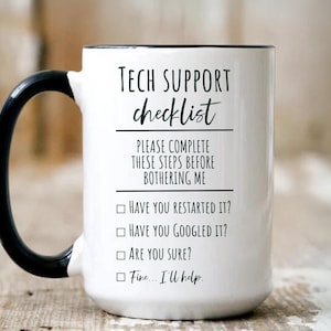May include: White ceramic mug with a black handle. The mug has black text that reads "TECH SUPPORT checklist PLEASE COMPLETE THESE STEPS BEFORE BOTHERING ME HAVE YOU RESTARTED IT? HAVE YOU GOOGLED IT? ARE YOU SURE? Fine... I'll help."