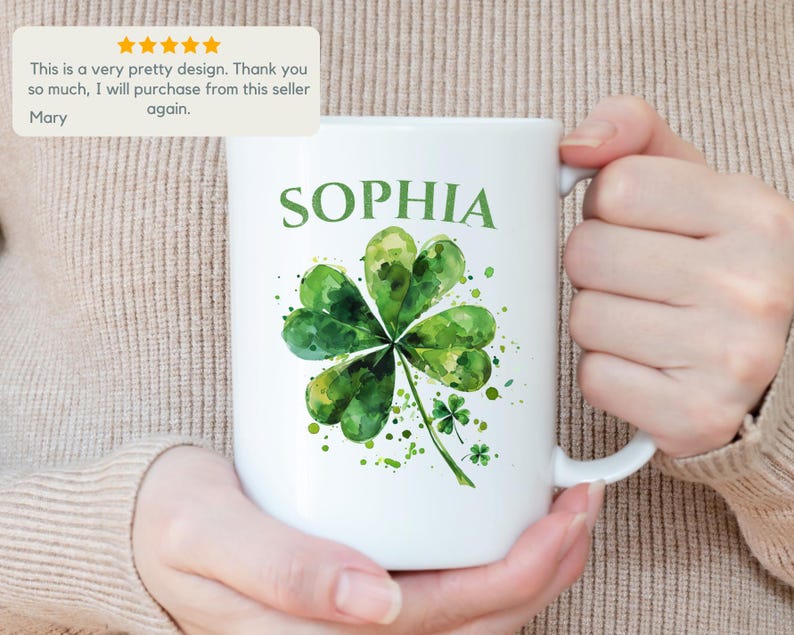 K&ouml;nnte beinhalten: Wei&szlig;e Keramiktasse mit einem gr&uuml;nen Aquarell-Kleeblatt-Design und dem Namen "SOPHIA" in Schwarz gedruckt.