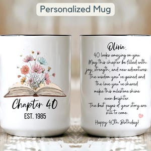 May include: White ceramic mug with black handle and rim, featuring floral and butterfly illustrations above an open book. Text reads "Chapter 40 EST. 1985" and a birthday message for Olivia.