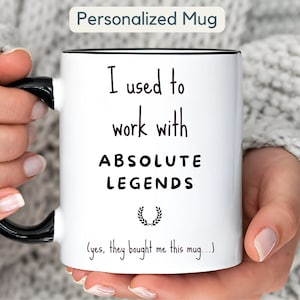 Può includere: Tazza in ceramica bianca con manico e bordo neri. La tazza presenta la scritta "I used to work with ABSOLUTE LEGENDS" in nero, con una grafica a corona d'alloro e la scritta "(yes, they bought me this mug...)". La tazza è etichettata "Personalized Mug".