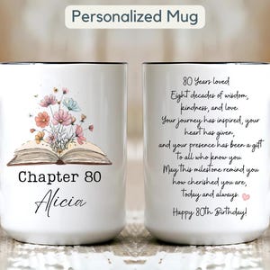 Puede incluir: Taza de cerámica blanca con asa y borde negros. Presenta un diseño floral sobre un libro abierto, el texto "Chapter 80 Alicia" y un mensaje de cumpleaños. La taza está personalizada para un 80 cumpleaños.