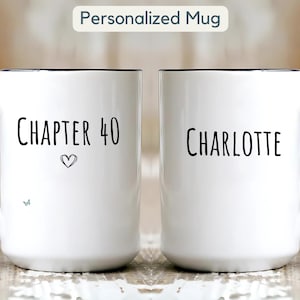 Könnte beinhalten: Zwei weiße Keramikbecher mit schwarzen Griffen und Rändern. Auf einem Becher steht "KAPITEL 40" mit einem Herzsymbol und einem kleinen Schmetterling. Auf dem anderen Becher steht "CHARLOTTE". Der Text "Personalized Mug" steht oben.