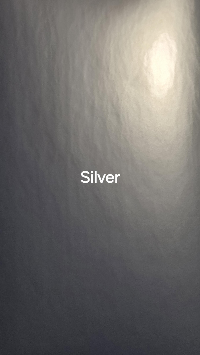 Puede incluir: Un fondo plateado texturizado con un &aacute;rea brillante e iluminada en la esquina superior derecha. La palabra "Silver" se muestra en blanco, centrada en la imagen.
