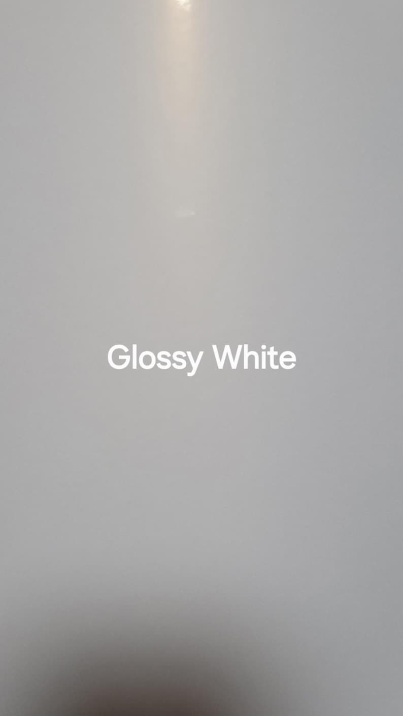Puede incluir: Primer plano de una superficie blanca brillante. Las palabras "Glossy White" est&aacute;n centradas en la superficie en una fuente blanca sans-serif. El fondo es un degradado de blanco y gris.