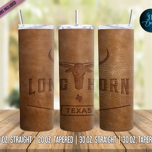 Op de afbeelding: Drie roestvrijstalen bekers met een bruin lederen ontwerp. De bekers hebben de woorden "LONGHORN" en "TEXAS" met een silhouet van een longhorn-stier. De bekers zijn verkrijgbaar in 20 oz. recht, 20 oz. taps toelopend, 30 oz. recht en 30 oz. taps toelopend.