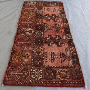 May include: A vintage Turkish runner rug with a geometric pattern in shades of red, brown, and cream. The rug has a faded, distressed look and is perfect for adding a touch of traditional style to any room.