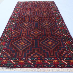 Puede incluir: Una alfombra persa tradicional con fondo azul oscuro y intrincados patrones geométricos en tonos rojos, verdes y amarillos. La alfombra tiene un borde con flecos.