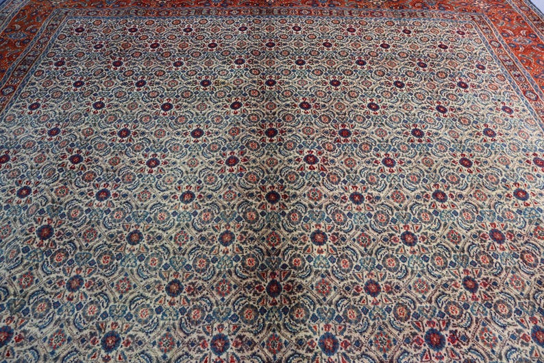 May include: A large rectangular area rug featuring an intricate repeating floral and geometric pattern in shades of cream, deep red, navy blue, and muted teal. The design consists of small circular medallions surrounded by dense botanical motifs.