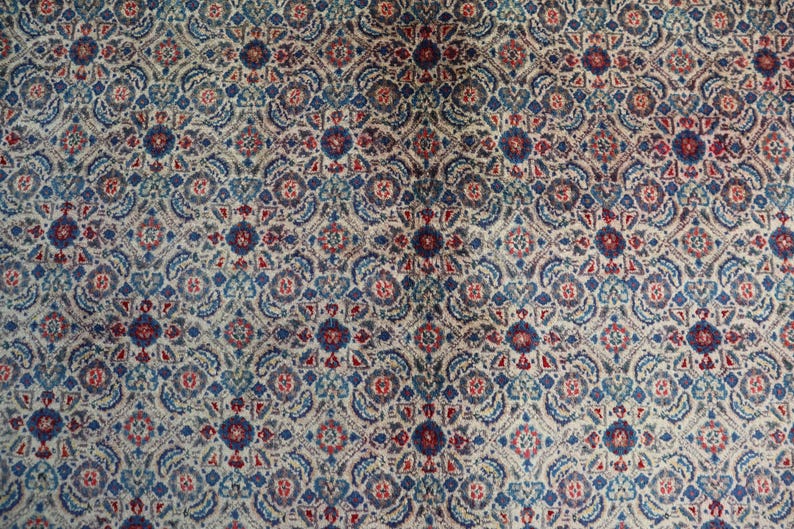 May include: A textile featuring a repeating geometric pattern in shades of deep blue, muted red, and cream. The design consists of interconnected floral-like medallions and intricate scrollwork arranged in a dense, symmetrical grid across the surface.