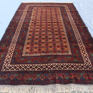 May include: A traditional Persian rug with a dark red background and intricate geometric patterns in shades of red, orange, blue, and green. The rug has a fringe border.