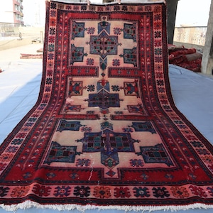 May include: A traditional Persian rug with a red, white and blue colour scheme. The rug has a geometric pattern with intricate details. The rug is made of wool and has a fringed border.