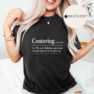 Puede incluir: Camiseta negra con la palabra "Centering" en blanco y una definición. La definición dice: "(v.) El acto de luchar contra un montón gris de barro hasta que uno de ustedes se rinda."