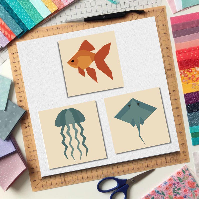 May include: Three square art prints featuring geometric sea creatures: a goldfish, a jellyfish, and a stingray. The fish is orange, the jellyfish is teal, and the stingray is grey. The prints are on a neutral background.