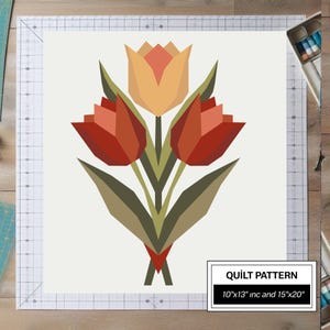 May include: A quilt pattern featuring a geometric illustration of three tulips in shades of red, orange, and yellow with olive green stems and leaves. The design includes text stating QUILT PATTERN 10"x13" inc and 15"x20" on a white background.