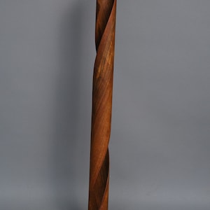 A wooden floor lamp with a twisted, brown wood base and a black cord.