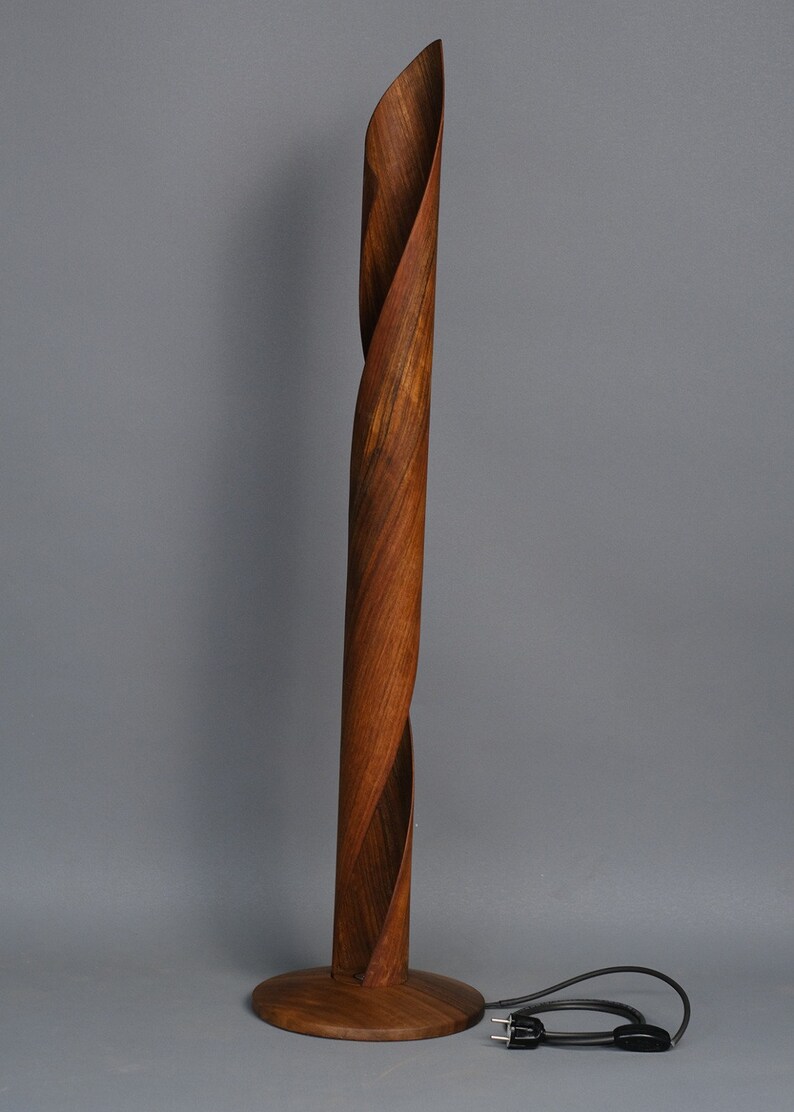 A wooden floor lamp with a twisted, brown wood base and a black cord.