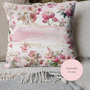May include: A decorative pillow with a floral design. The pillow features a watercolor-style print of pink and white flowers, with the words "I love spring" in the center. The pillow is surrounded by other pillows and a blanket.