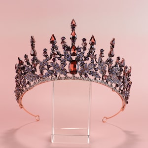 May include: A gold crown with purple and red gemstones. The crown is decorated with intricate leaf designs.