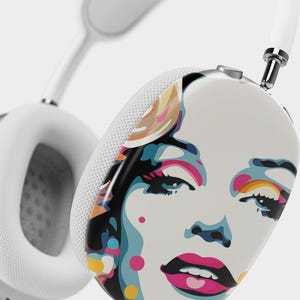 May include: White wireless headphones with a colorful pop art design featuring a woman's face on one earcup.
