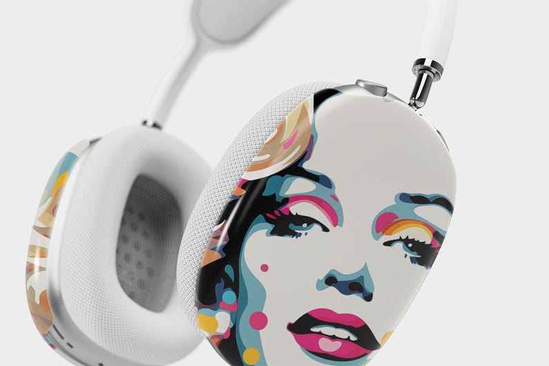 May include: White wireless headphones with a colorful pop art design featuring a woman's face on one earcup.