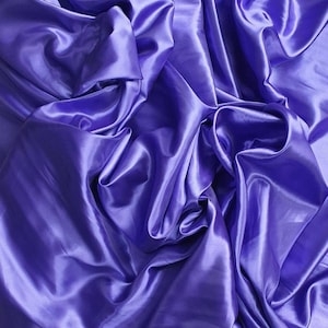 May include: A close-up of a smooth, silky fabric in a vibrant purple hue. The fabric is draped and folded, creating soft, flowing lines and a luxurious feel.