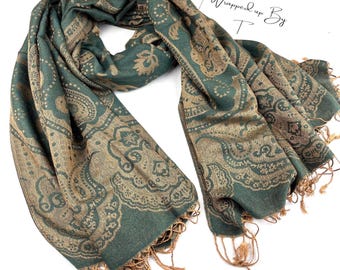 Könnte beinhalten: Ein grüner und goldener Schal mit einem komplizierten Paisley-Muster und Fransen. Der Schal ist drapiert und zeigt das detaillierte Design und die Textur. Der Text "Wrapped up By T" ist in der oberen rechten Ecke sichtbar.