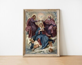 May include: Framed religious artwork depicting three figures in flowing robes, with a central female figure in a blue gown. The painting features cherubic figures and a dove, set against a cloudy background. The frame is a light wood color.