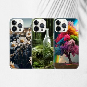 May include: Three iPhone cases with different designs. The first case features a close-up of white daisies against a dark green background. The second case shows a green forest scene with a glass bottle. The third case has a colourful tree with a rainbow in the background.