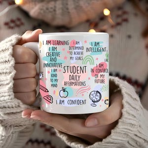 Puede incluir: Taza de cerámica blanca con un diseño colorido que presenta afirmaciones positivas para estudiantes. El texto incluye "Estoy aprendiendo", "Soy creativo", "Soy amable con mi mente", "Soy estudiante afirmaciones diarias", "Estoy en control de mi futuro", y "Confío en mí".