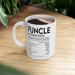 May include: White ceramic coffee mug with a black handle. The mug has a black graphic that reads "FUNCLE Nutrition Facts" with a list of humorous nutritional facts.