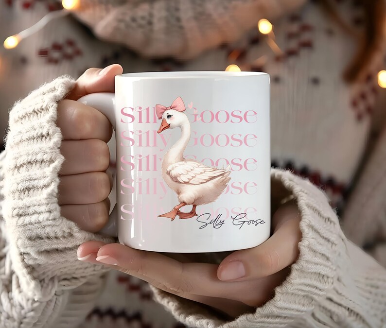 May include: White ceramic mug featuring a whimsical illustration of a goose wearing a pink bow. The mug has the words "Silly Goose" repeated in a pink font. The goose is light pink with orange feet and beak.