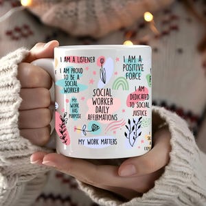 Könnte beinhalten: Eine weiße Keramiktasse mit bunten Illustrationen und Text, der "Social Worker Daily Affirmations" lautet. Der Text enthält Sätze wie "Ich bin ein Zuhörer", "Ich bin eine positive Kraft", "Meine Arbeit hat einen Sinn" und "Meine Arbeit zählt".