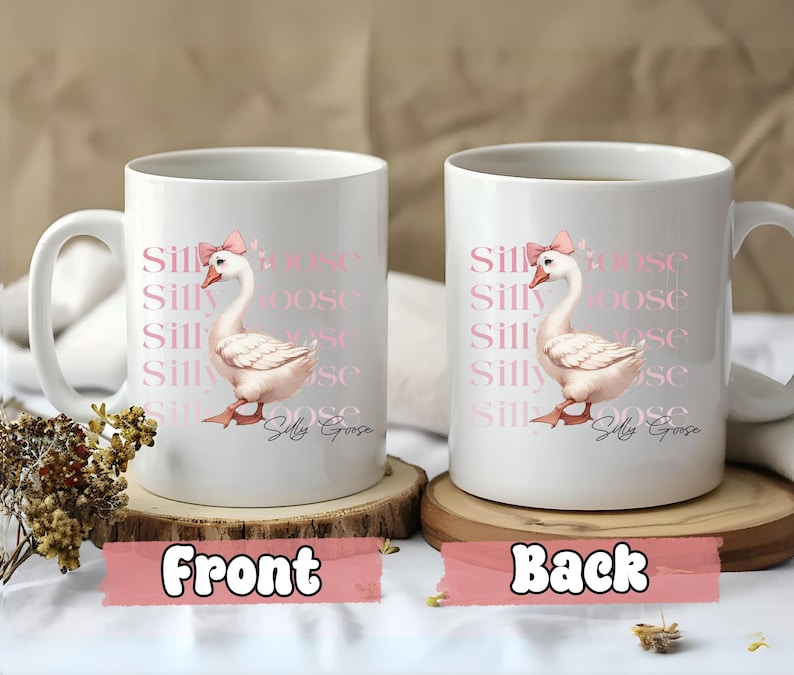 May include: White ceramic mug featuring a pink goose illustration wearing a bow, with the words "Silly Goose" repeated vertically. The mug has a handle and is displayed on a wooden coaster.