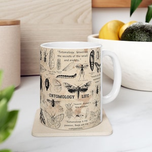 Peut inclure: Une tasse en céramique blanche avec une illustration en noir et blanc d'insectes et le texte "Entomology: Unveiling the secrets of the small and mighty."  "Insects: Nature's tiny wonders."  "Entomology is my passion, bugs are my companions."