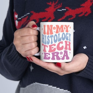 Può includere: Una tazza in ceramica bianca con un design colorato che dice "In My Histology Tech Era".