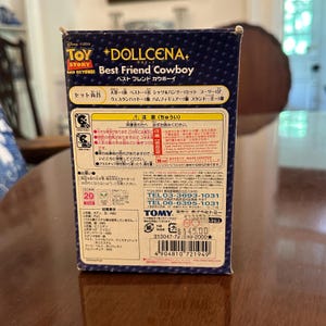 May include: A Toy Story "Best Friend Cowboy" doll set in a box. The box features Japanese text and illustrations, including the Toy Story logo and the Dollcena logo. The set includes a doll, clothing, and accessories.