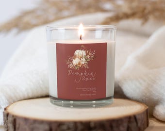 May include: A glass jar candle with a red label that says "Pumpkin Spice". The label features a watercolor illustration of white pumpkins and fall foliage.