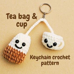 Puede incluir: Un llavero de ganchillo hecho a mano con un diseño de bolsita de té y taza de té. La bolsita de té es blanca y marrón, y la taza de té es blanca. Ambos tienen caras sonrientes con ojos negros. También se ve el texto "Tea bag & cup" y "Keychain crochet pattern".