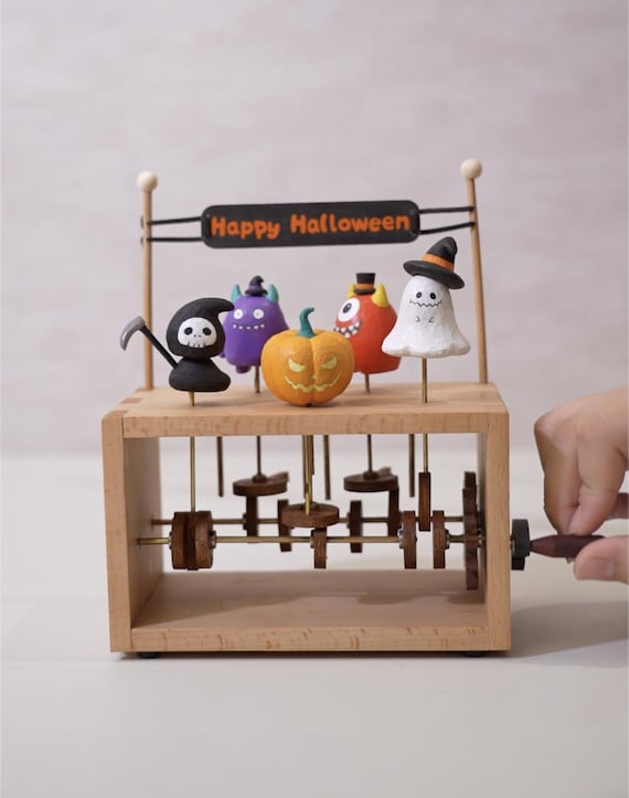 A hand-carved wooden Halloween automaton where pumpkins, ghosts, and the Grim Reaper actually dance via mechanical linkage — the kind of heirloom-quality spooky art piece you'd never find at a big-box store.