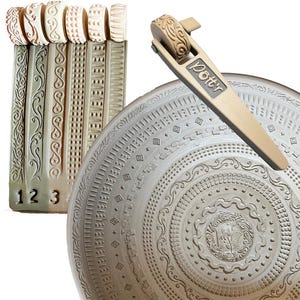 Könnte beinhalten: Ein Satz von fünf Tonstempeln mit verschiedenen Mustern sowie ein Tonwalzenwerkzeug mit einem dekorativen Muster. Das Walzenwerkzeug hat einen Griff mit dem aufgedruckten Wort "Potter". Die Tonstempel sind mit 1, 2 und 3 nummeriert.