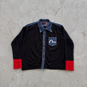 May include: Black button-up shirt with a denim collar and pocket. The shirt features red cuffs and a white logo on the denim pocket. The shirt has a denim button strip down the front.