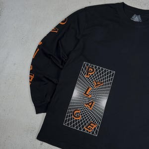 May include: Black long-sleeve t-shirt with an orange "PALACE" graphic on a white grid background.