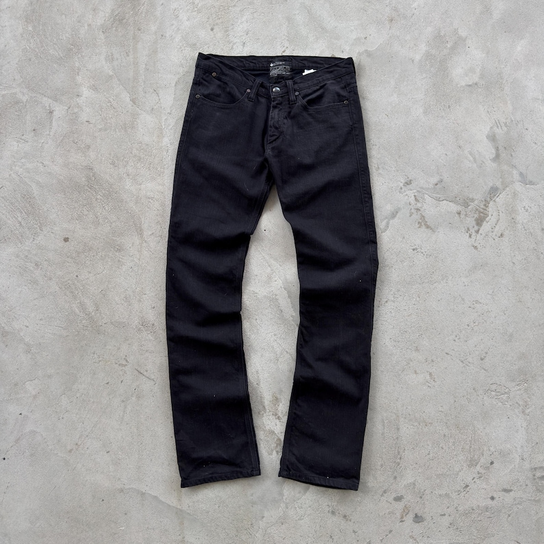 May include: A pair of black denim jeans. The jeans have a classic five-pocket design, a button and zipper closure, and a straight leg fit. The jeans are made of a sturdy, dark-colored denim material.