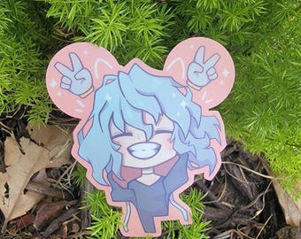 May include: A sticker featuring a cartoon character with blue hair, wearing a black shirt and making a peace sign with both hands. The sticker has a pink background with white stars and a white outline.
